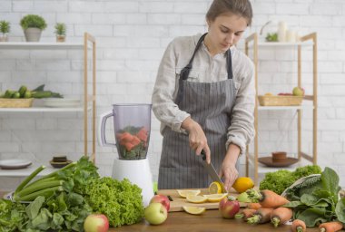 Genç bir kadın sebzeli sebze suyu hazırlıyor, narenciye.