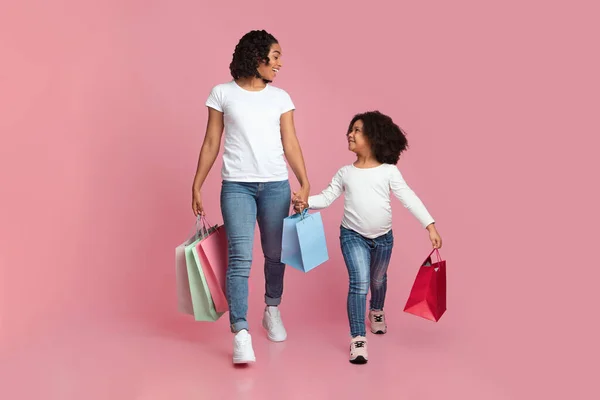 Alegre madre negra e hija caminando con muchas bolsas de compras coloridas —  Fotos de Stock