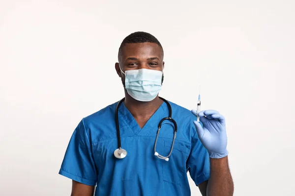 戴着面罩和手套拿着注射器的黑人医生 — 图库照片