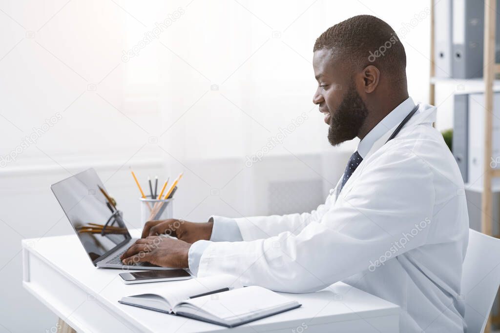 Hard-working african therapist sending emails in his office