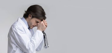 Steteskopu elinde olan depresif erkek doktorun profili.
