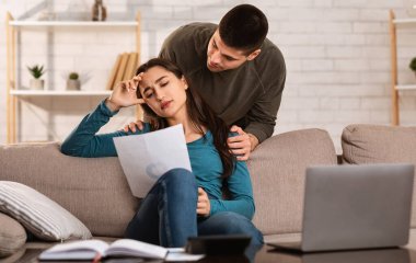 Genç koca, hayal kırıklığına uğramış karısını koltukta teselli ediyor.