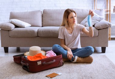 Tatil için bavulda eşyalar. Ellerinde maske olan kadın