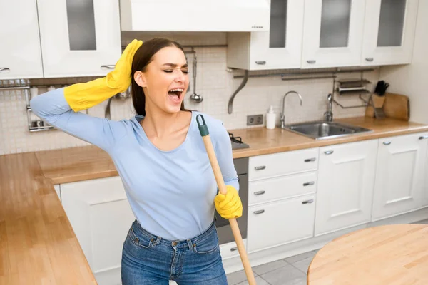 Happy young woman cleaning floor singing at mop — Stock Photo, Image