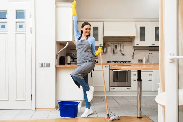 Jonge vrouw schoonmaken keuken vloer dansen met dweil — Stockfoto