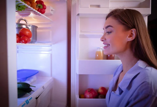 Young woman looking for healthy snack in fridge late in night — Stock Photo, Image