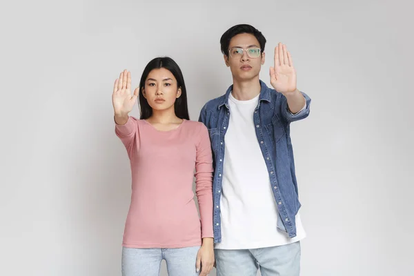 Jeune couple asiatique debout sur fond gris, faire stop signe — Photo