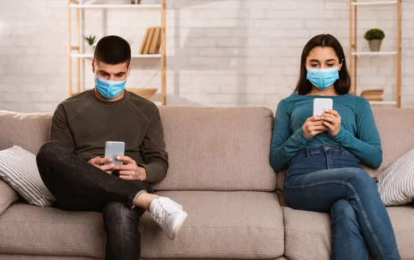 Couple wearing surgical mask using cell phones — Stock Photo, Image