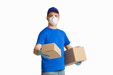 Tıbbi maskeli teslimatçı bir kutu uzatıyor.