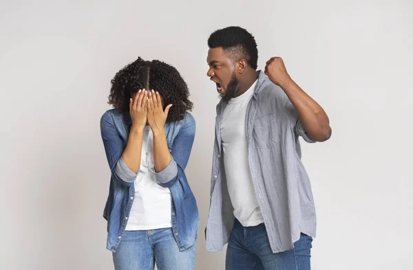 Violencia doméstica. Enojado hombre negro amenazando a su novia con el puño —  Fotos de Stock