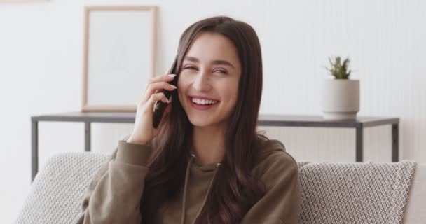 Chica milenaria positiva hablando por teléfono celular en casa — Vídeo de stock