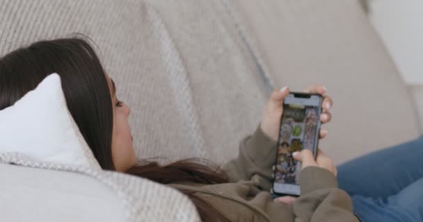 Молодая девушка прокручивает приложение в социальных сетях по мобильному телефону — стоковое видео