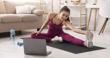 Kendini izole ederken aktif kal. Evdeki dizüstü bilgisayarda esneyen ve video izleyen güzel bir kız. Panorama