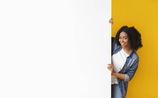 Щаслива чорна жінка дивиться з порожньої білої рекламної дошки — стокове фото