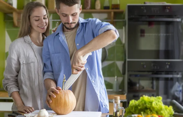 Attraktiv man skär en pumpa med kniv på en skärbräda — Stockfoto