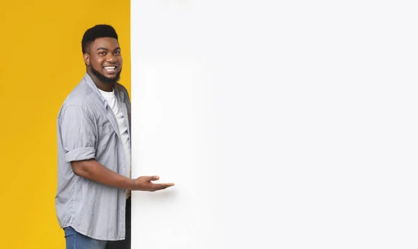 Homem negro feliz apontando para placa de publicidade branca com palma aberta — Fotografia de Stock