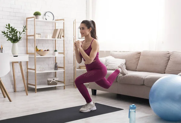 At home workout routine. Latin girl training indoors, doing lunges near sofa — Stock Photo, Image