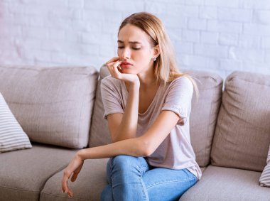 Kişisel izolasyon kavramı. Düşünceli kız kanepede oturur.