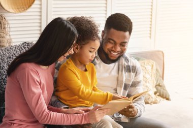 Smiling international parents teach child to read clipart