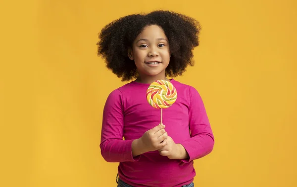 Schattig klein Afrikaans Amerikaans meisje met lolly snoep in handen — Stockfoto