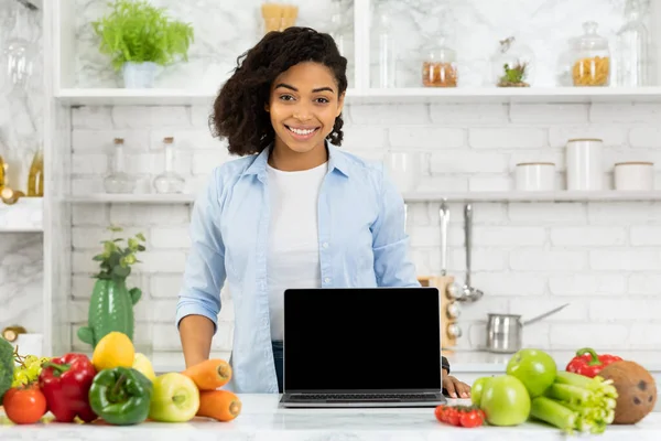 Черная девушка показывает ноутбук на кухне — стоковое фото
