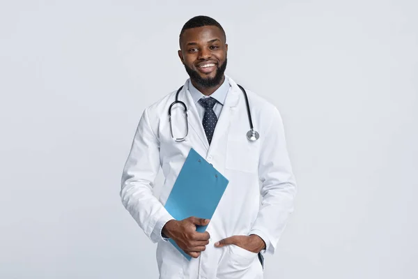 Joven médico africano feliz sosteniendo la historia clínica — Foto de Stock