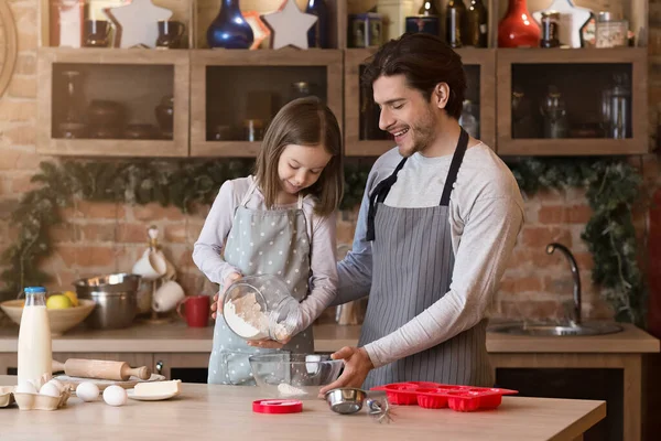 Küçük kız babasının pişirmesine yardım ediyor, kase için un ekliyor. — Stok fotoğraf