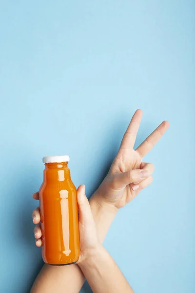 Uma garrafa de suco de laranja ou bebida de desintoxicação em uma mão de mulher — Fotografia de Stock