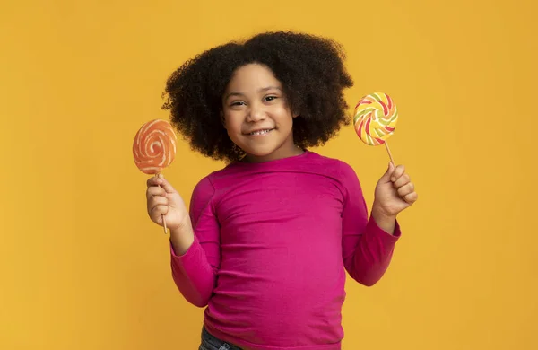 Twee kleurrijke lolly 's in handen van schattig Afrikaans Amerikaans meisje — Stockfoto
