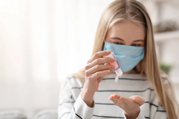 Jonge vrouw in beschermende masker gieten ontsmettingsmiddel op handen — Stockfoto
