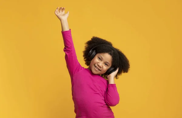 Schattig Afrikaans meisje dansen terwijl genieten van haar favoriete muziek in draadloze hoofdtelefoon — Stockfoto