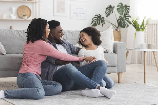 Vrolijke zwarte familie hebben plezier thuis, ouders kietelen hun dochter — Stockfoto