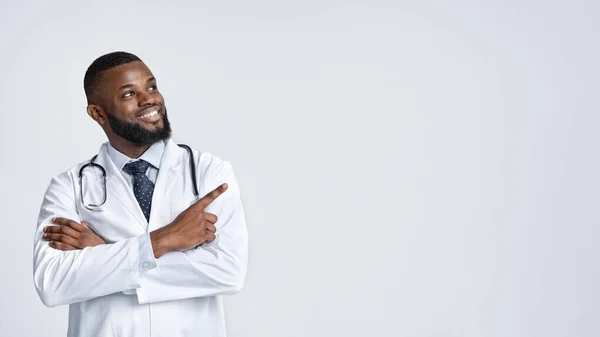 积极的非洲医生，双手交叉，指向空旷的空间 — 图库照片