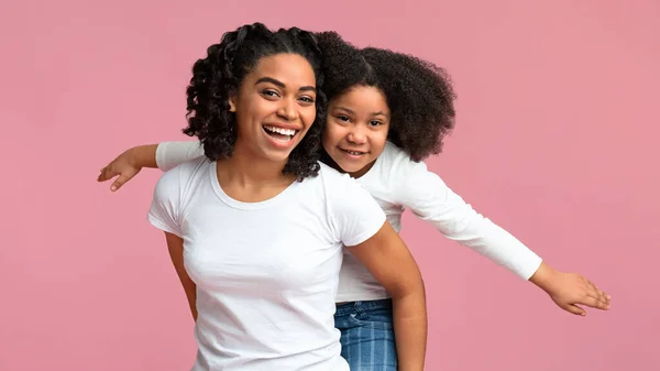 Feliz negro mujer dando piggyback paseo a su adorable hija — Foto de Stock