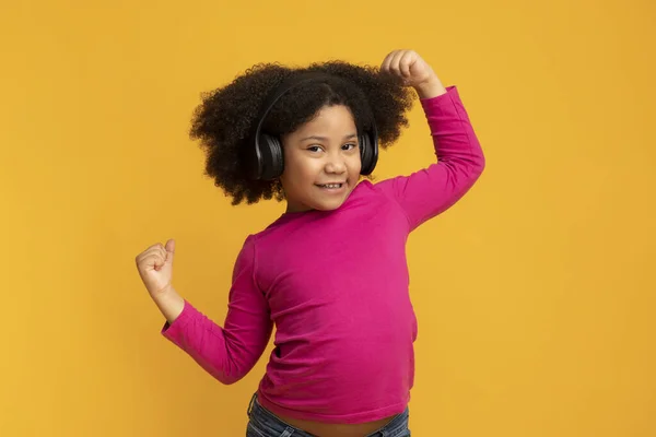 Pozitivní legrační africký americký dívka na sobě bezdrátové sluchátka a tanec — Stock fotografie