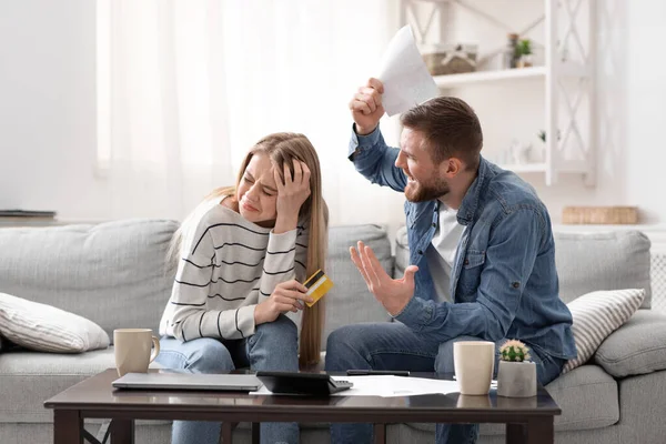 Wütender Ehemann brüllt seine schuldige Frau zu Hause mit riesigen Kreditkartenrechnungen an — Stockfoto