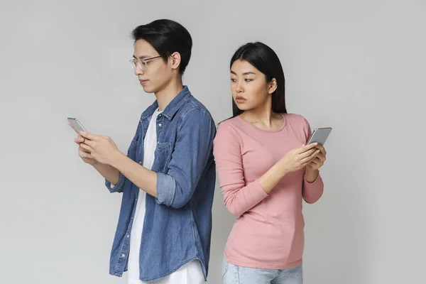 Asyalı kız, erkek arkadaşı telefon kullanırken onu gözetliyor. — Stok fotoğraf
