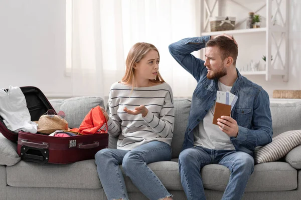 Upset couple with flight tickets unpacking suitcase at home