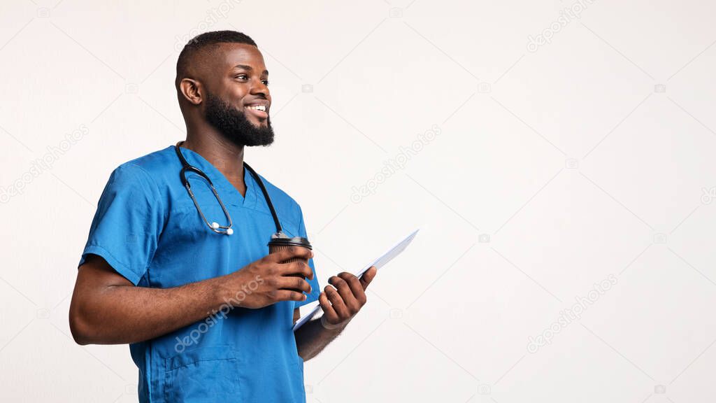 Smiling black doctor holding medical chart and drinking coffee