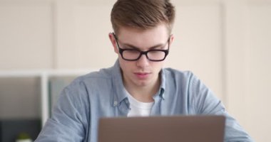 Genç ciddi serbest çalışan ev bilgisayarında çalışıyor.