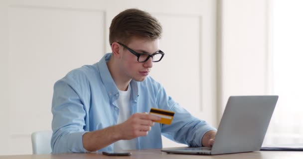 Jongeman invoeren van credit card gegevens en beveiligings wachtwoord van mobiele telefoon op laptop — Stockvideo