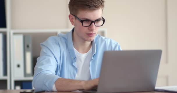 Müde von der Arbeit am Computer reibt sich junger Mann die Augen — Stockvideo