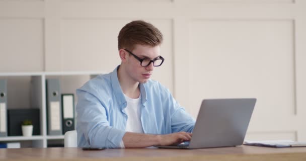 Ung kille masserar nacken, arbetar fjärrstyrt på laptop — Stockvideo