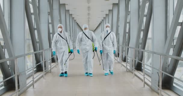 Grupo de desinfectantes en materiales peligrosos que caminan en el edificio público — Vídeos de Stock