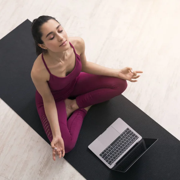 COVID-19 자립심. 라틴 소녀가 요가 교습을 노트북으로 받고, 호흡 운동이나 명상을 하고, 위에서 본 광경 — 스톡 사진