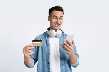 İnternetten alışveriş konsepti. Akıllı telefonlu kulaklıklı bir adam.