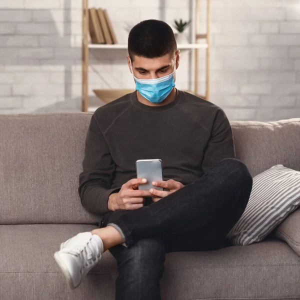Человек в хирургической маске с помощью смартфона — стоковое фото