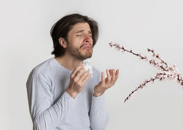 Man smelling flowers and suffer from allergies — Stock Photo, Image