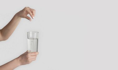 Tanımlanamayan bir kadın arka planda bir bardak suya hap ekliyor. Yakın plan. Boş boşluk