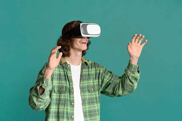 Modern entertainment. Millennial guy in virtual reality headset playing video games on turquoise background — Stock Photo, Image